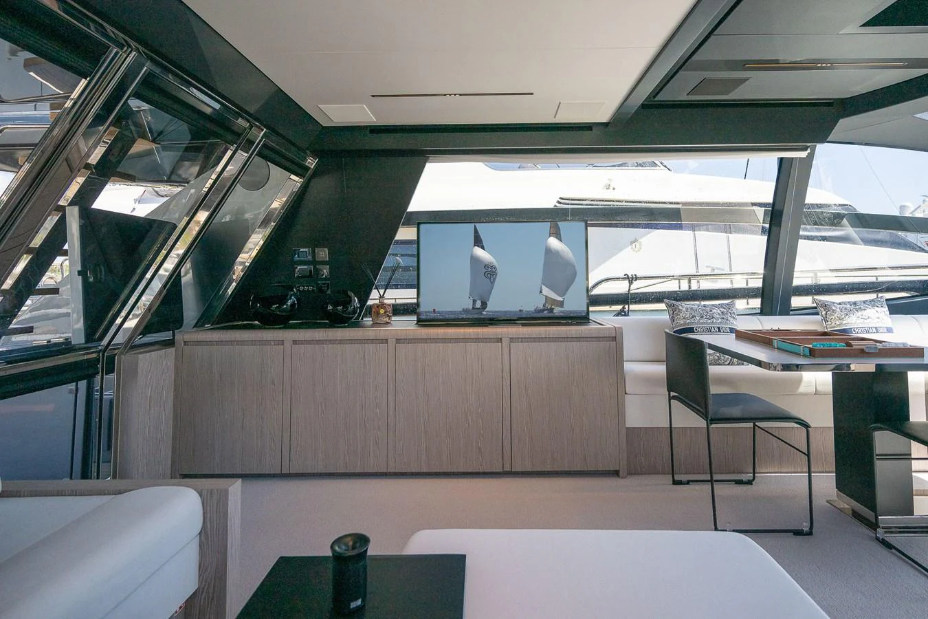 The modern interior of the yacht features large windows, sleek furnishings, and a comfortable seating area. aboard ACQUA Yacht for Sale