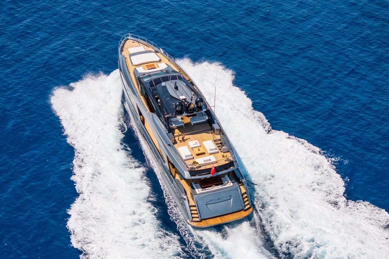 A sleek yacht cruises through the open sea, leaving a trail of white water behind. aboard JANETTE Yacht for Sale