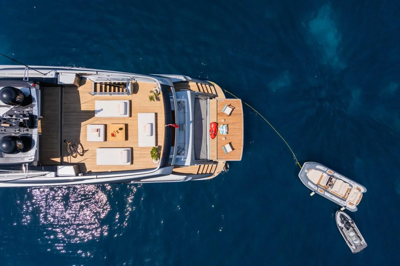An aerial view of the yacht's aft deck showcasing a spacious lounging area and tender boats in the water. aboard JANETTE Yacht for Sale
