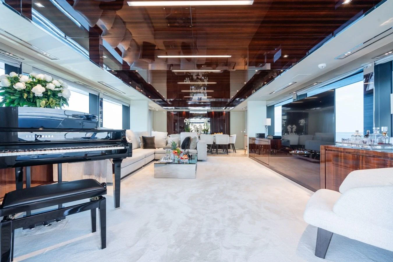 The luxurious interior features a spacious and elegant living area with a grand piano and plush seating. aboard JANETTE Yacht for Sale