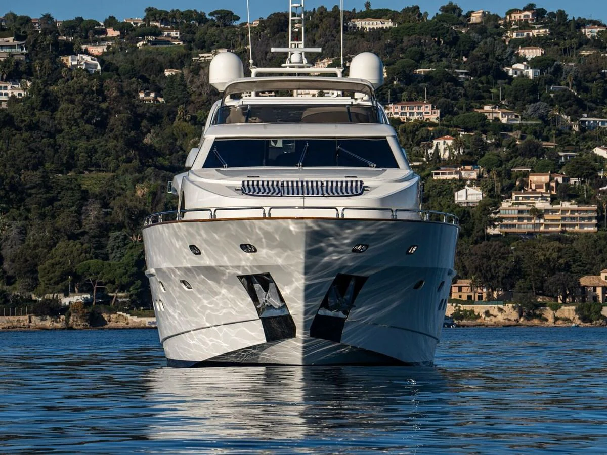 A luxurious yacht is anchored in calm waters with a scenic coastal backdrop. aboard SPRING TIDE Yacht for Sale