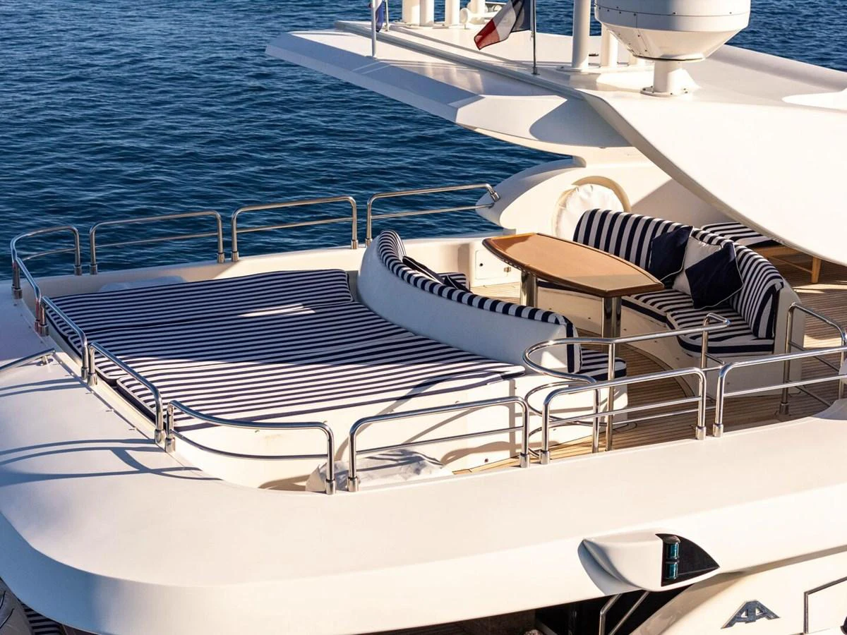 The sundeck offers a luxurious lounging area with striped cushions and a dining table, perfect for relaxation and socializing. aboard SPRING TIDE Yacht for Sale
