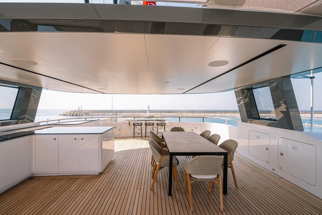 The aft deck features a spacious dining area with modern furnishings and panoramic views. aboard RAISA Yacht for Sale
