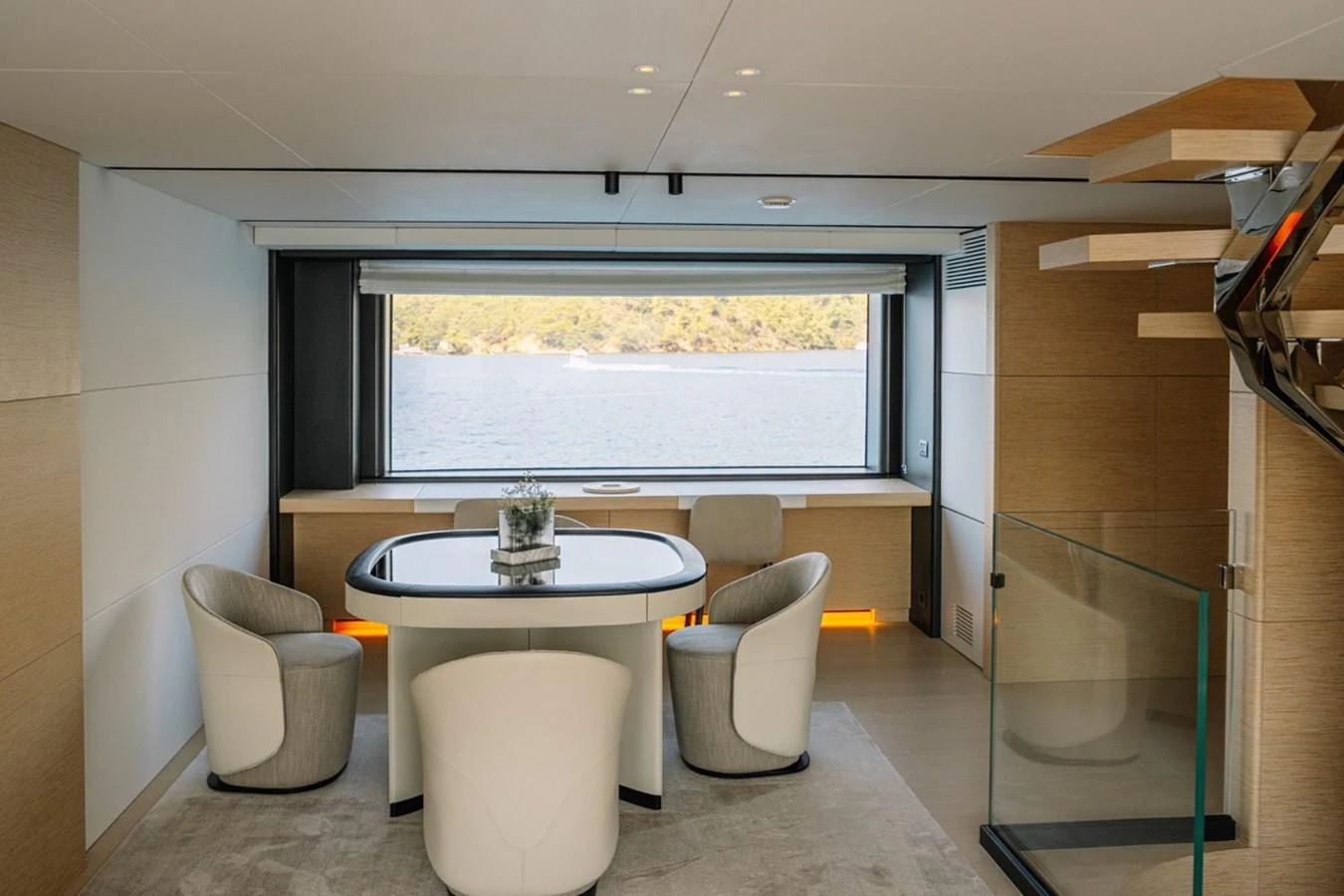A stylish dining area with a scenic view through a large window. aboard RAISA Yacht for Sale