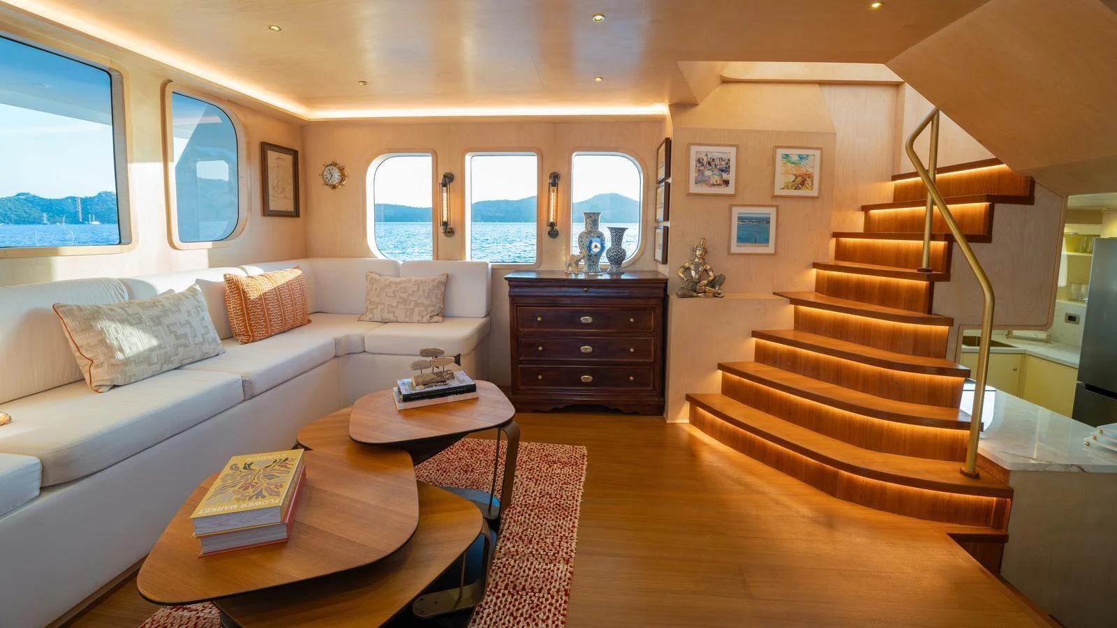 The salon features a cozy seating area with elegant decor and a beautifully lit staircase. aboard TROYWIZARD Yacht for Sale