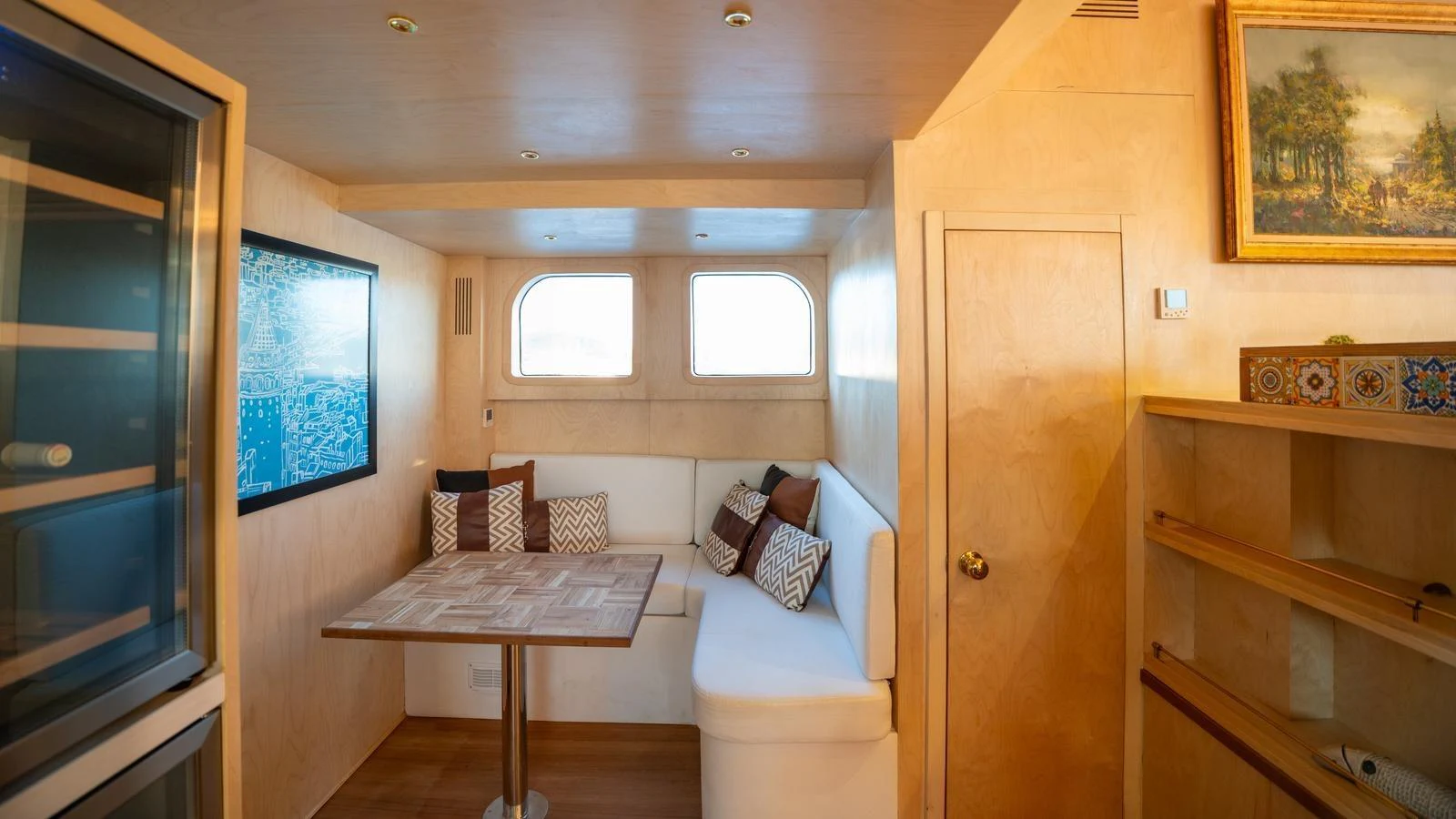 A cozy dining area with a built-in bench and a wooden table, complemented by a large window and tasteful decor. aboard TROYWIZARD Yacht for Sale