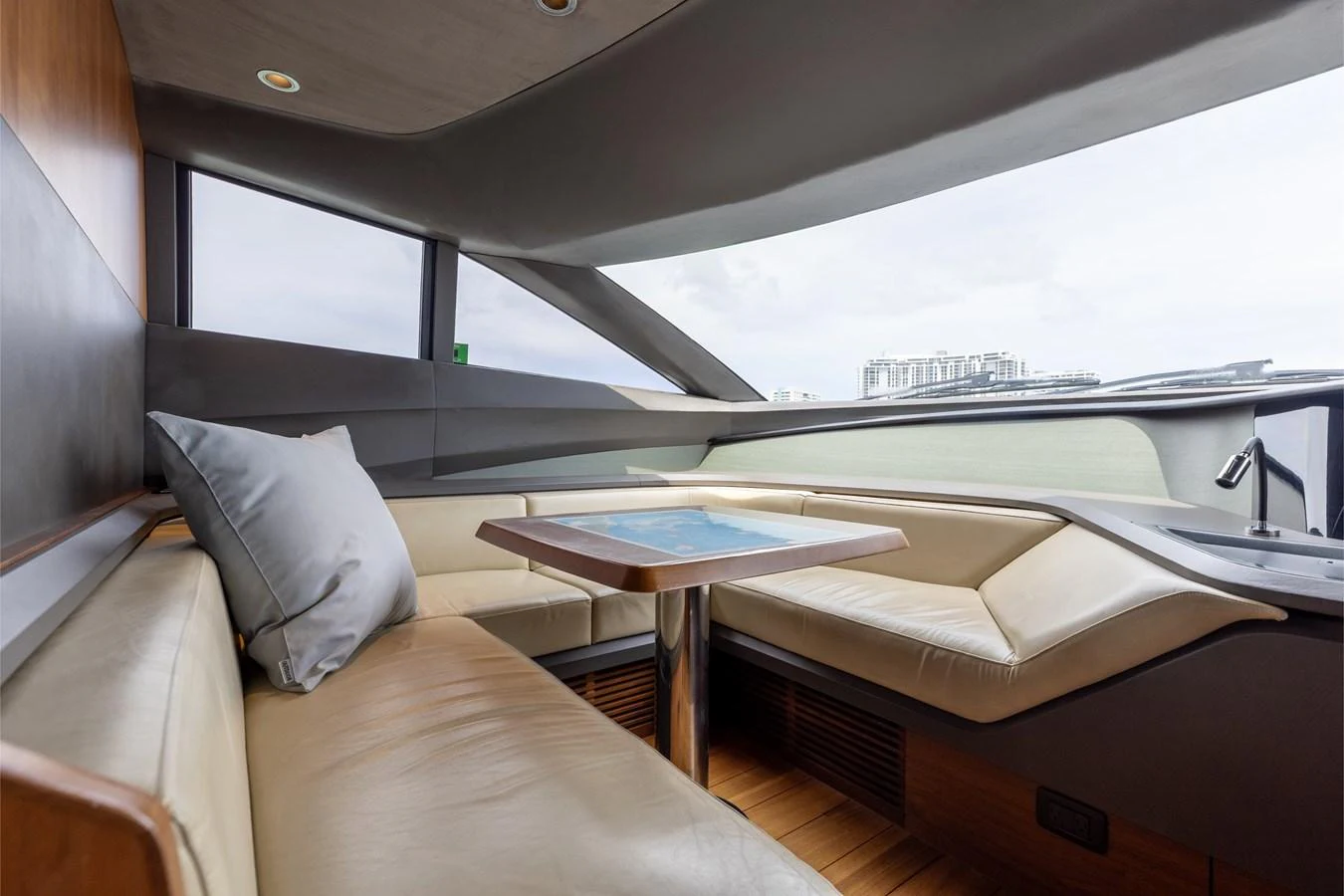 The saloon features a comfortable seating area with a table, offering panoramic views through large windows. aboard TOMORROW NEVER KNOWS Yacht for Sale