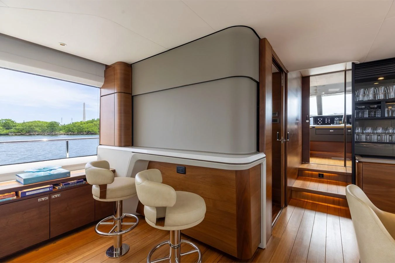 The yacht's salon features elegant bar seating and a view of the water through large windows. aboard TOMORROW NEVER KNOWS Yacht for Sale