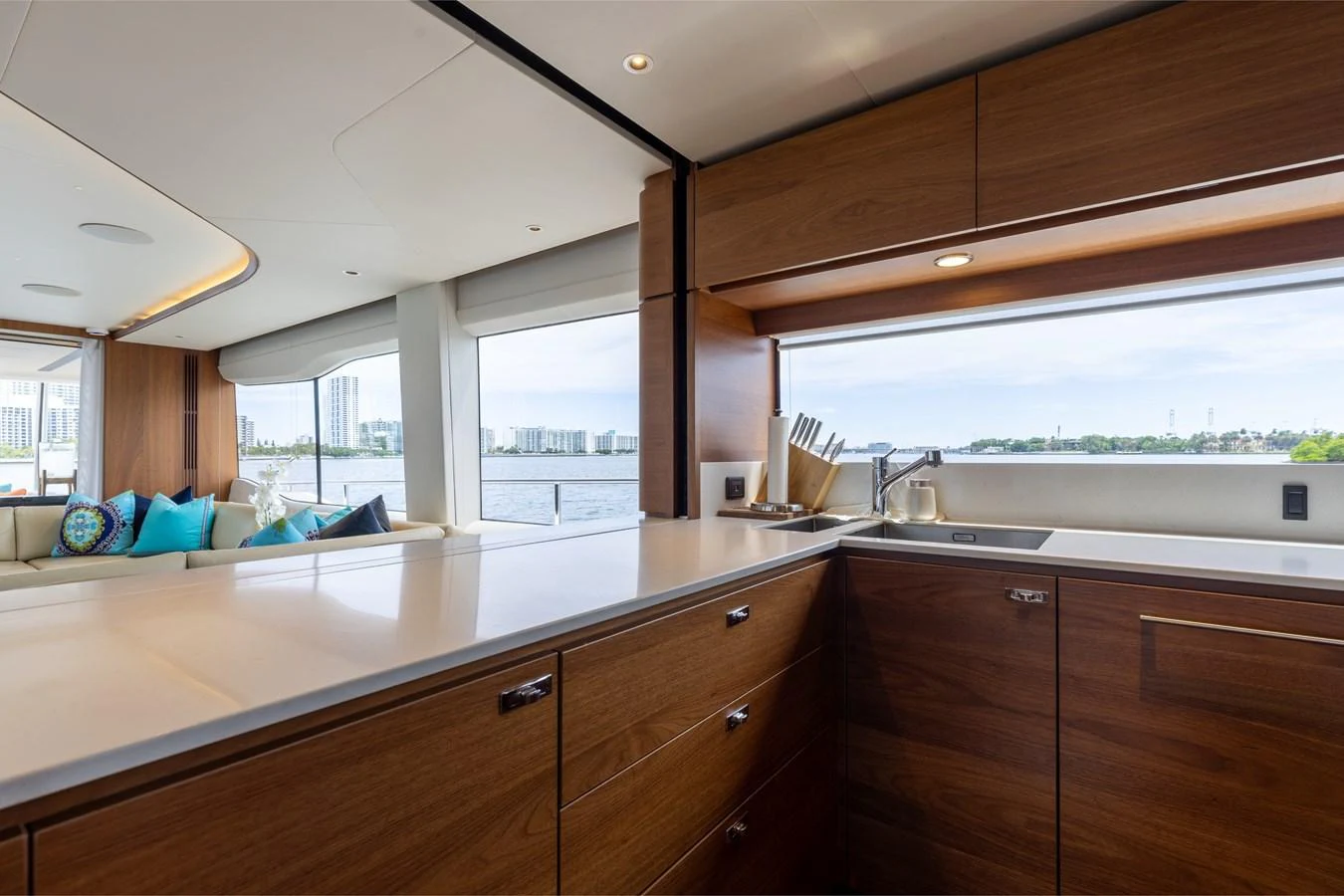 The yacht's galley features modern wooden cabinetry and expansive windows with a view of the water. aboard TOMORROW NEVER KNOWS Yacht for Sale