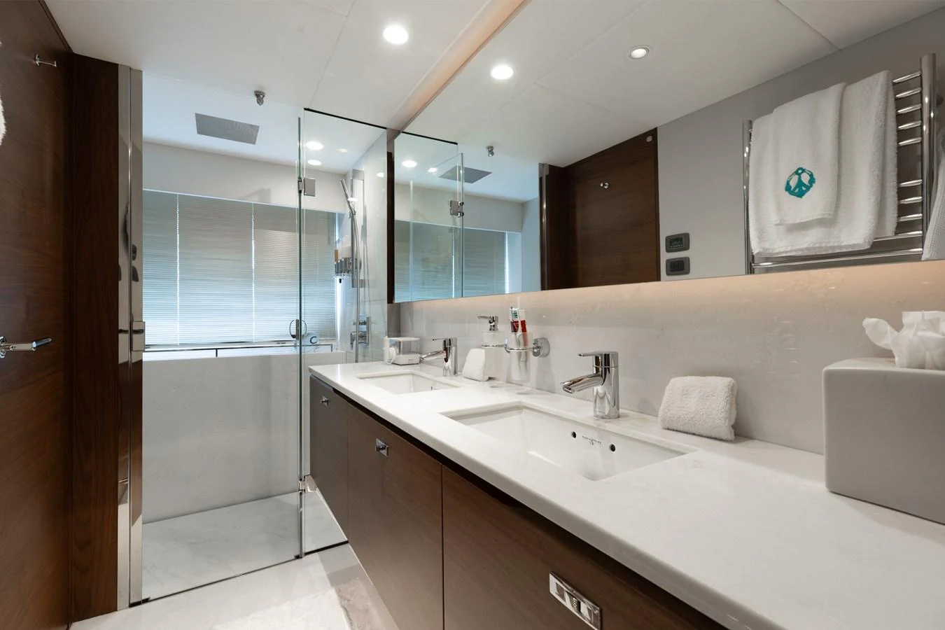 The yacht's bathroom features a modern design with dual sinks and a spacious shower area. aboard TOMORROW NEVER KNOWS Yacht for Sale