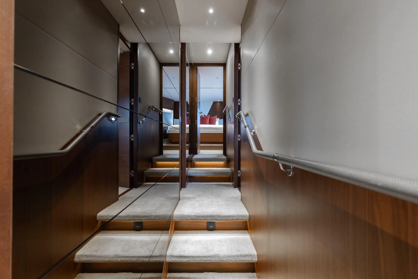 A luxurious hallway with carpeted steps and sleek wooden paneling leads to a well-lit room. aboard TOMORROW NEVER KNOWS Yacht for Sale