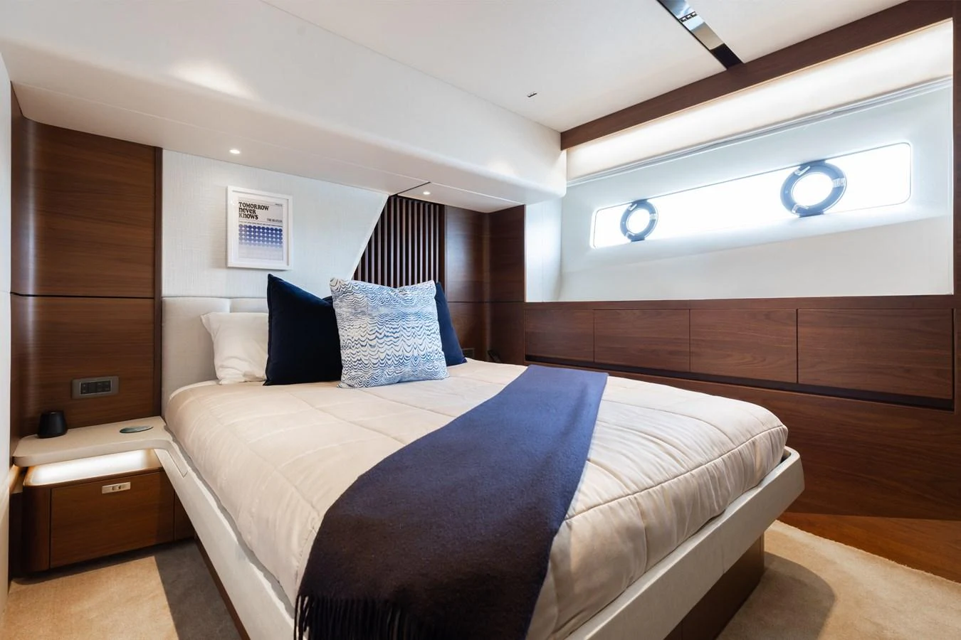 The stateroom features a luxurious bed with elegant wooden accents and ample natural light. aboard TOMORROW NEVER KNOWS Yacht for Sale