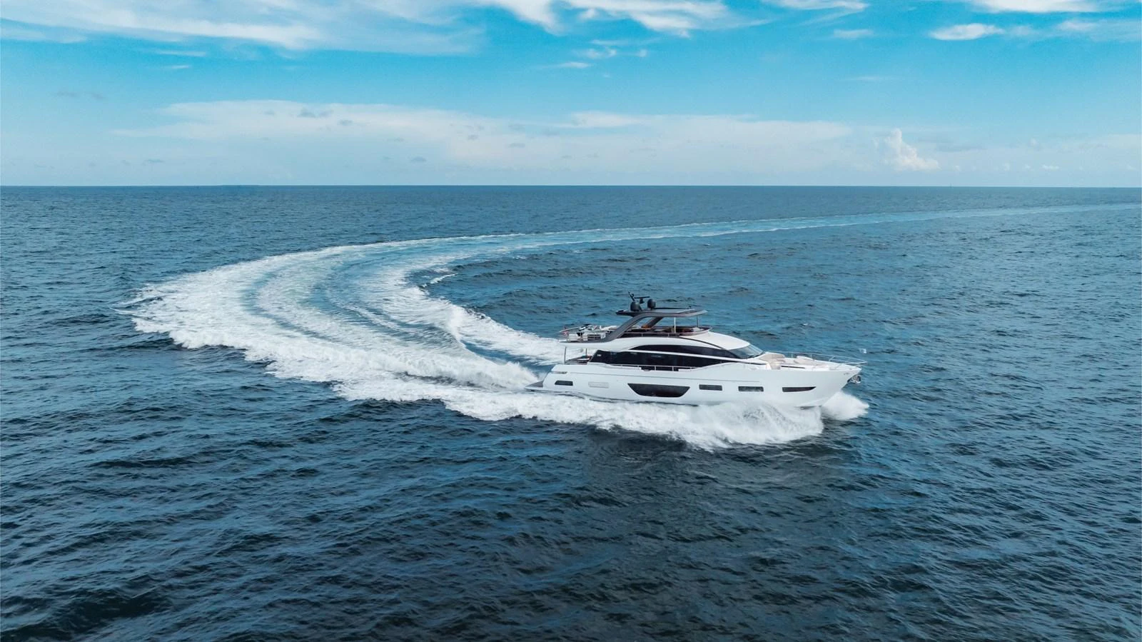 A sleek yacht cruises through open waters, leaving a graceful wake behind. aboard TOMORROW NEVER KNOWS Yacht for Sale