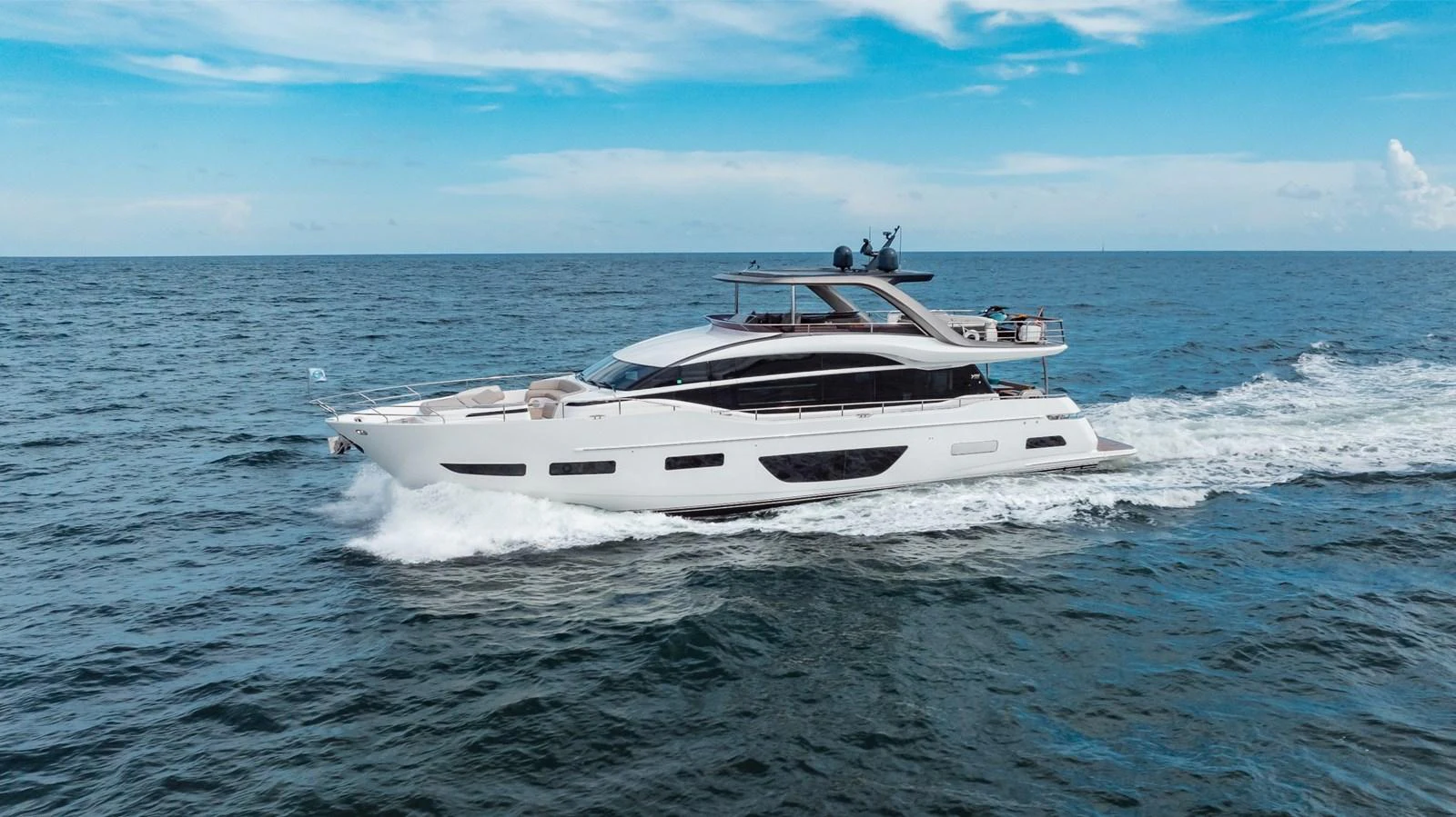 A sleek and modern yacht cruising through open waters under a clear blue sky. aboard TOMORROW NEVER KNOWS Yacht for Sale