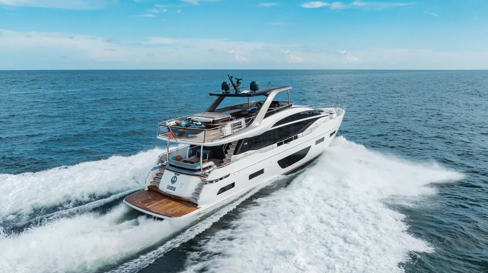 A sleek and modern yacht cruises swiftly through open waters under a clear blue sky. aboard TOMORROW NEVER KNOWS Yacht for Sale