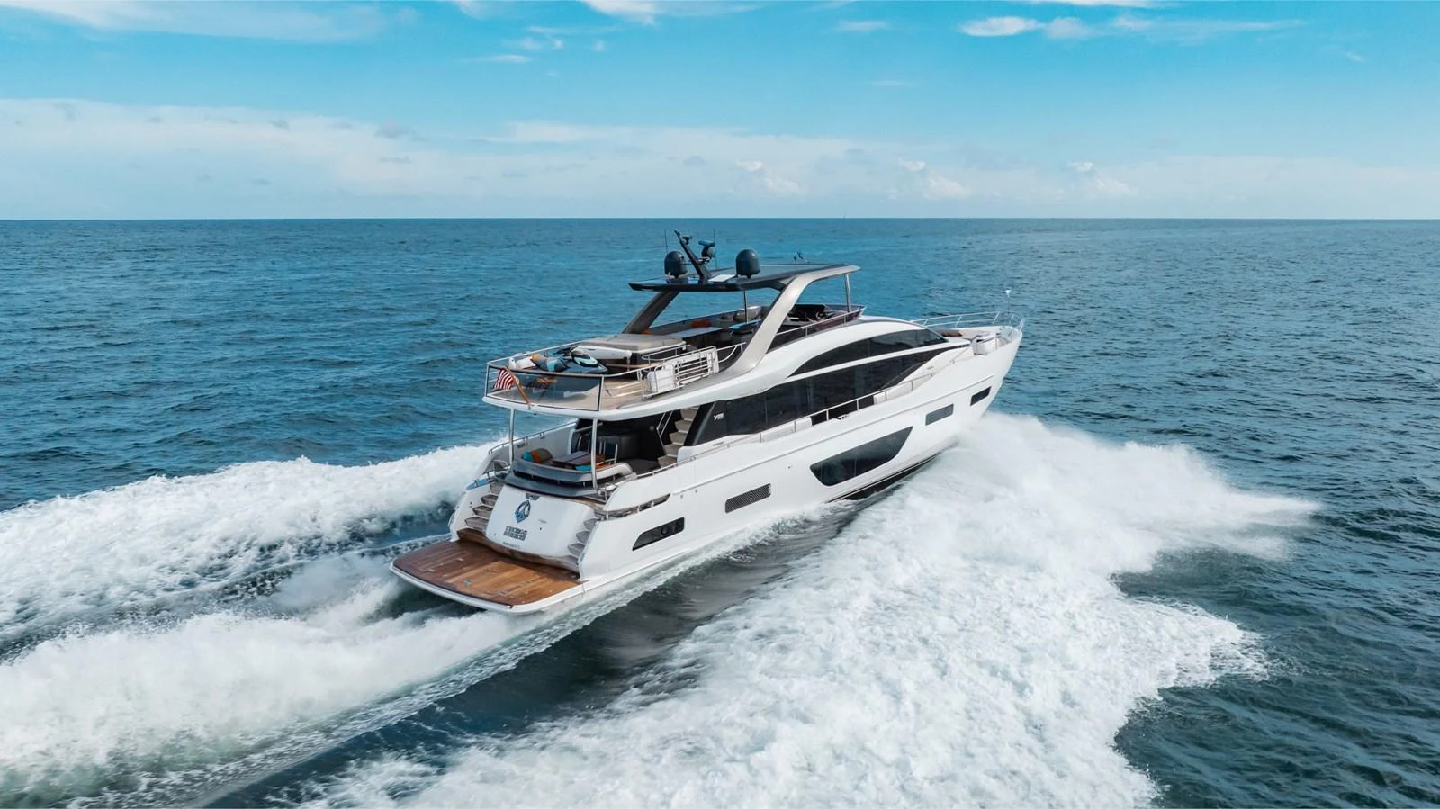 A sleek and modern yacht cruises swiftly through open waters under a clear blue sky. aboard TOMORROW NEVER KNOWS Yacht for Sale