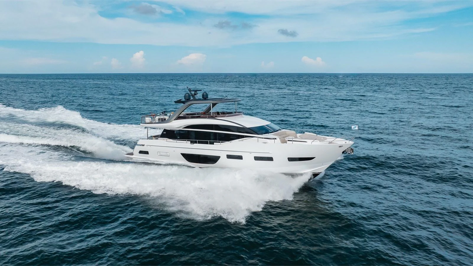 A sleek and modern yacht cruises swiftly through the open sea under a clear blue sky. aboard TOMORROW NEVER KNOWS Yacht for Sale