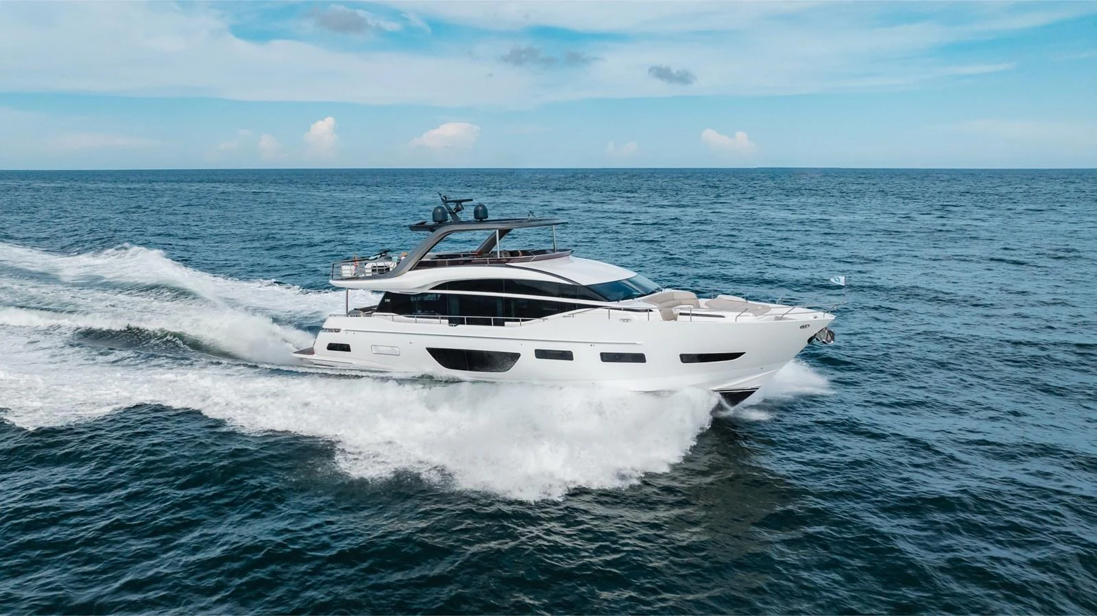 A sleek and modern yacht cruises swiftly through the open sea under a clear blue sky. aboard TOMORROW NEVER KNOWS Yacht for Sale