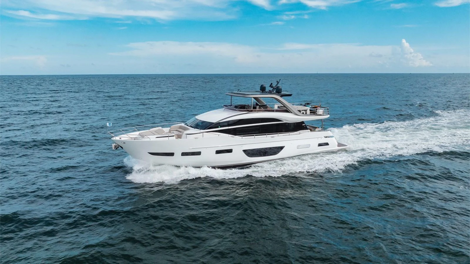 A sleek and modern yacht cruises gracefully on open waters under a clear blue sky. aboard TOMORROW NEVER KNOWS Yacht for Sale