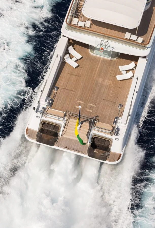 The yacht's aft deck features a spacious layout with lounge chairs and a view of the wake trailing behind. aboard ZEUS Yacht for Sale
