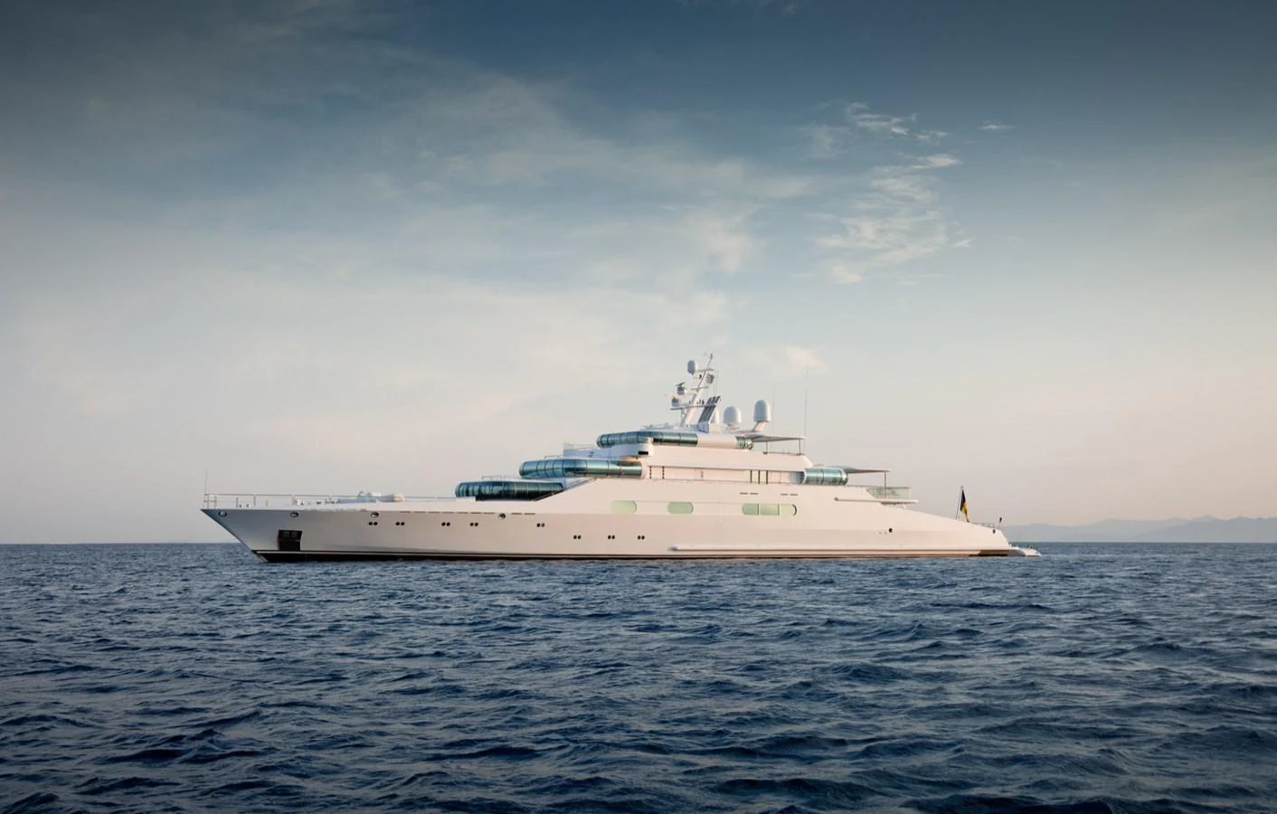 A sleek and modern yacht glides gracefully on the open sea under a clear sky. aboard ZEUS Yacht for Sale