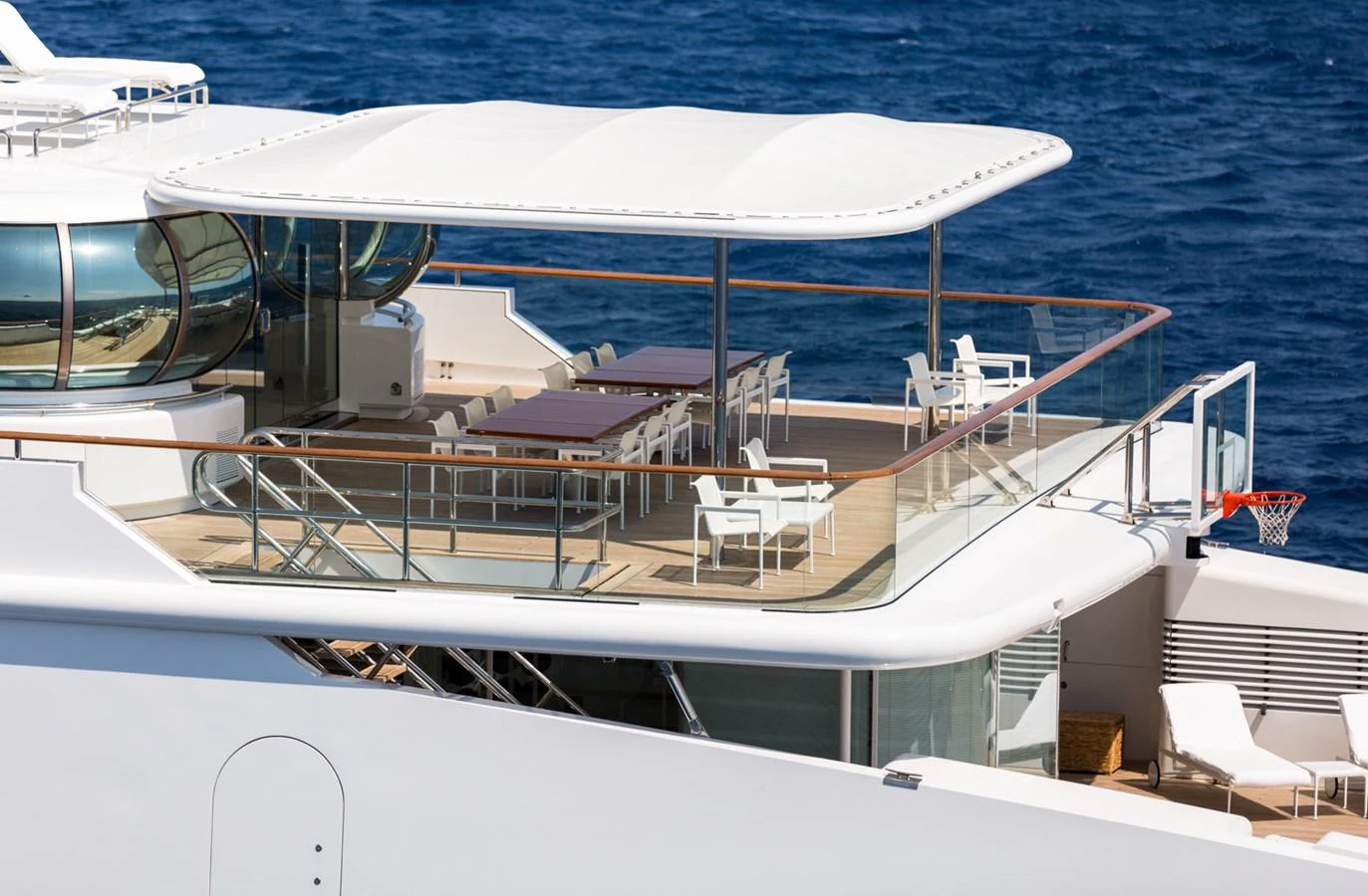 The yacht's upper deck features a spacious outdoor dining area with a modern canopy and elegant seating arrangements. aboard ZEUS Yacht for Sale