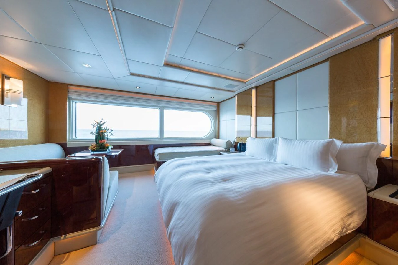 The stateroom features a luxurious bed with ample natural light from large windows. aboard ZEUS Yacht for Sale