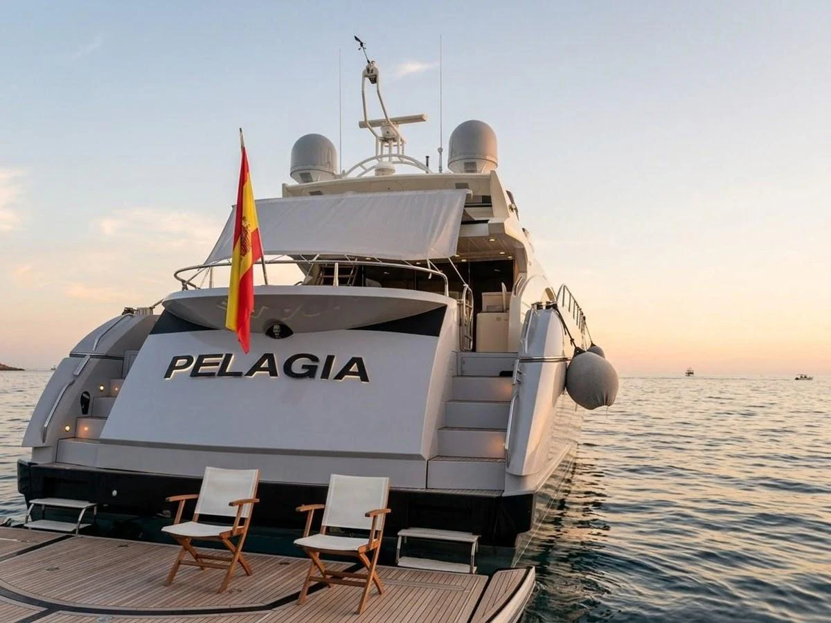 The yacht is anchored at sunset, showcasing its elegant stern with a spacious swim platform and comfortable seating. aboard PELAGIA Yacht for Sale