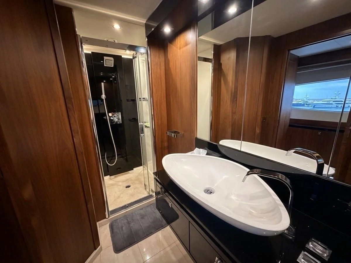 The yacht's bathroom features a sleek sink and a modern shower area with elegant wood paneling. aboard PELAGIA Yacht for Sale