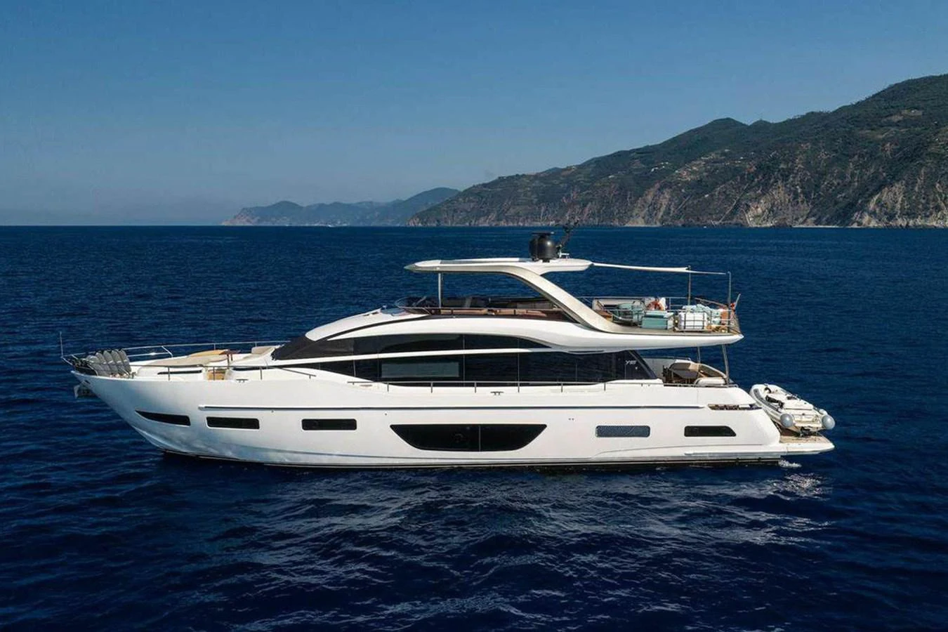 A sleek and modern yacht cruising on calm blue waters with a scenic coastline in the background. aboard AHAVA IV Yacht for Sale