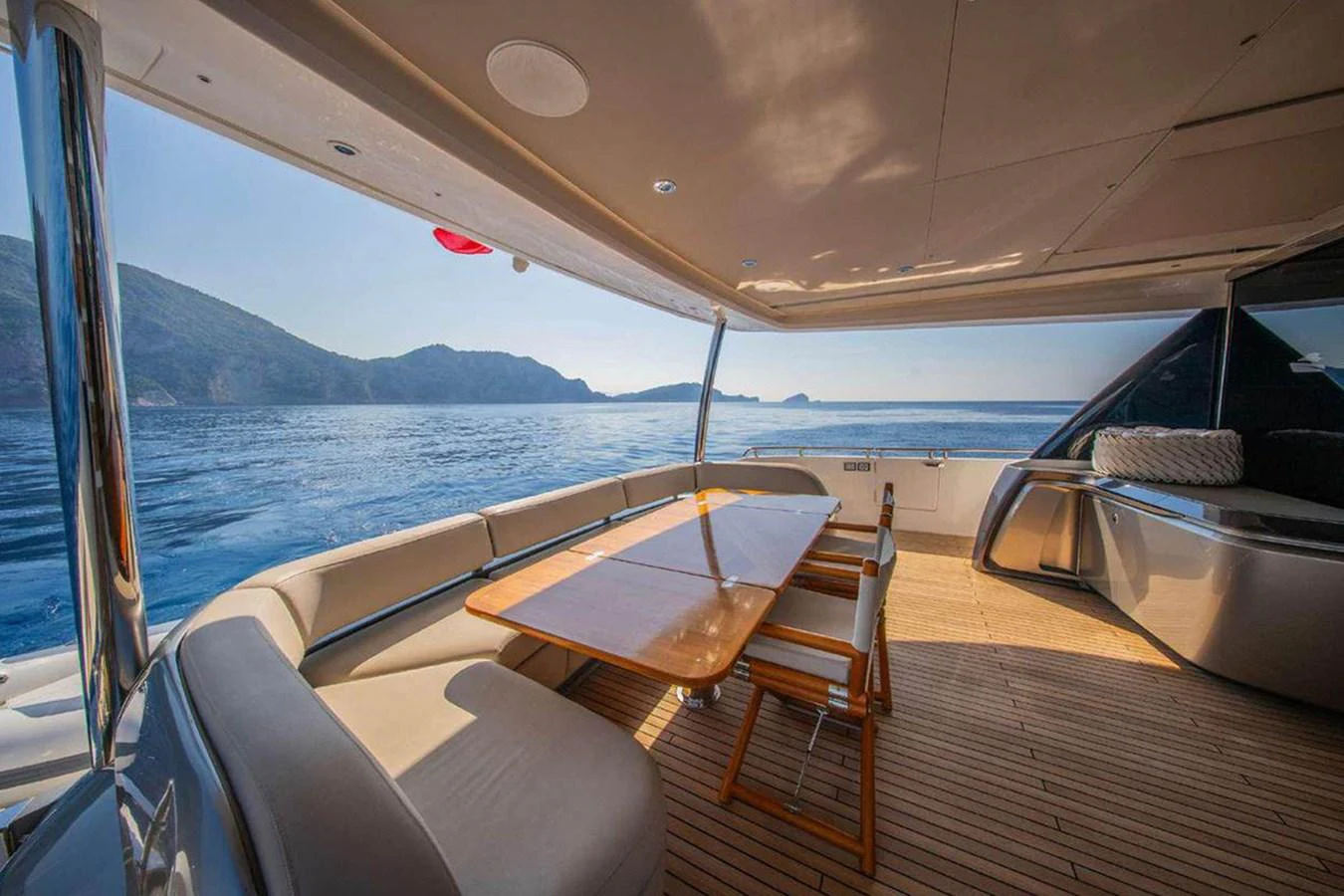 The aft deck features a spacious seating area with a wooden table, offering stunning views of the surrounding waters. aboard AHAVA IV Yacht for Sale