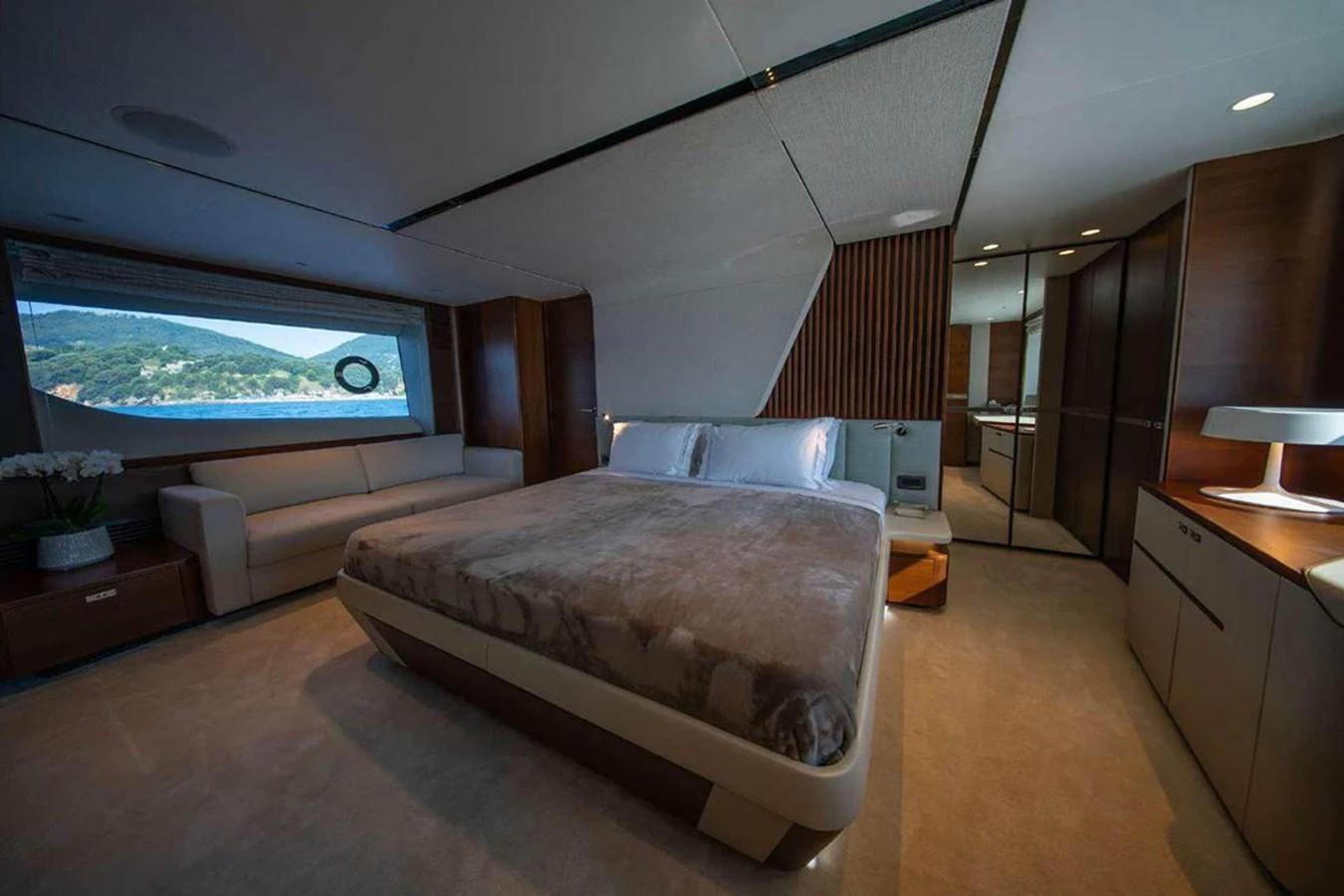 The master stateroom features a luxurious bed, ample seating, and a scenic window view. aboard AHAVA IV Yacht for Sale