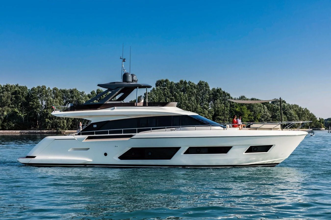 A sleek and modern yacht glides gracefully on calm waters with a backdrop of lush greenery. aboard LIVI B Yacht for Sale
