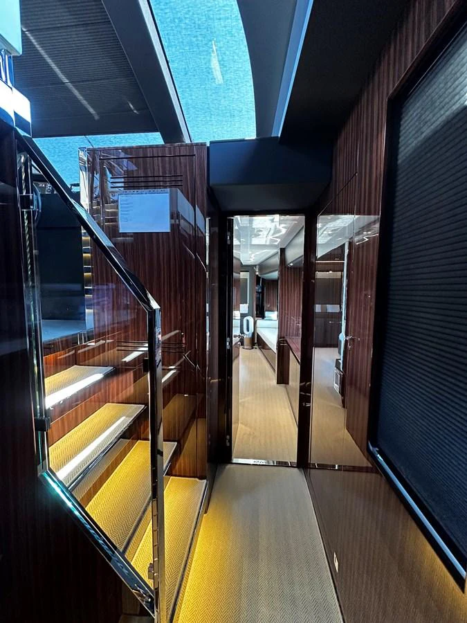 A sleek and modern hallway with wooden paneling and illuminated stairs. aboard 4SEAS Yacht for Sale