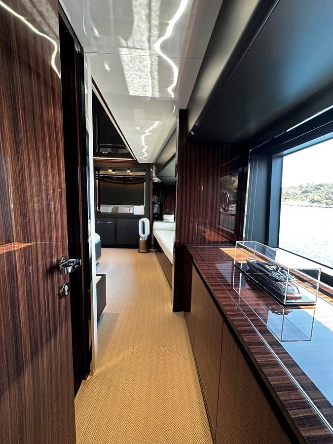 The yacht's interior hallway features sleek wood paneling and large windows offering scenic views. aboard 4SEAS Yacht for Sale