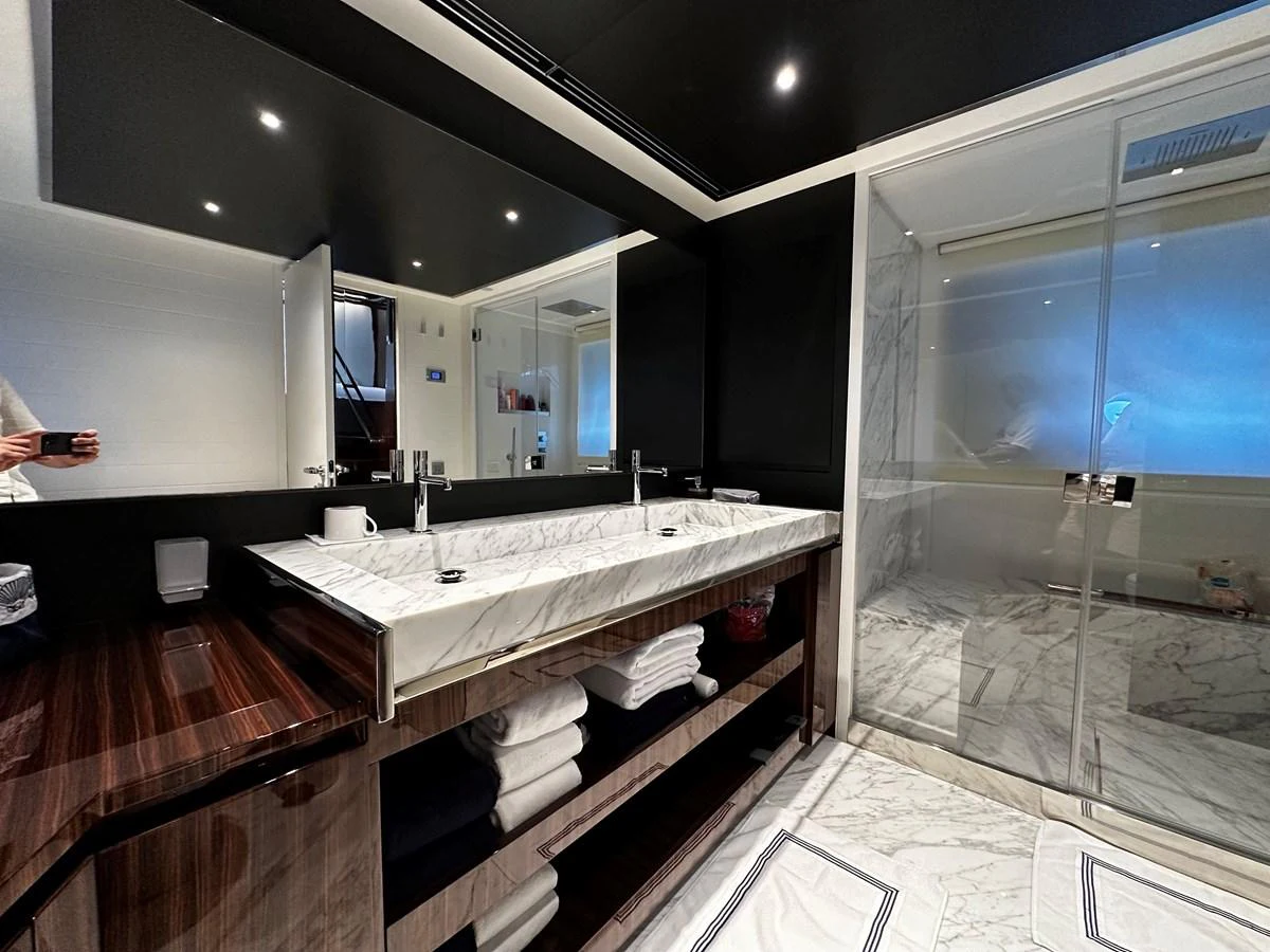 The yacht's bathroom features a luxurious double sink vanity and a spacious glass-enclosed shower. aboard 4SEAS Yacht for Sale