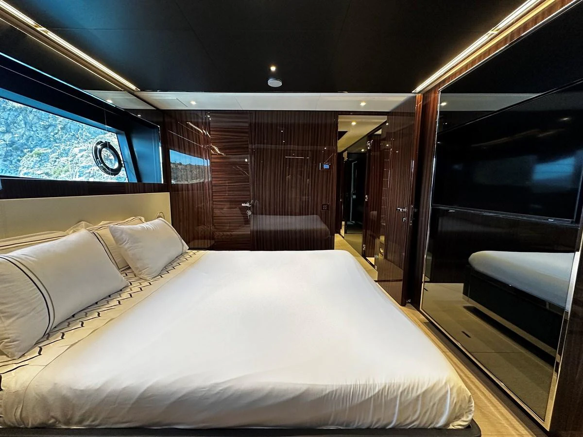 The stateroom features a luxurious bed with elegant wood paneling and ample natural light. aboard 4SEAS Yacht for Sale