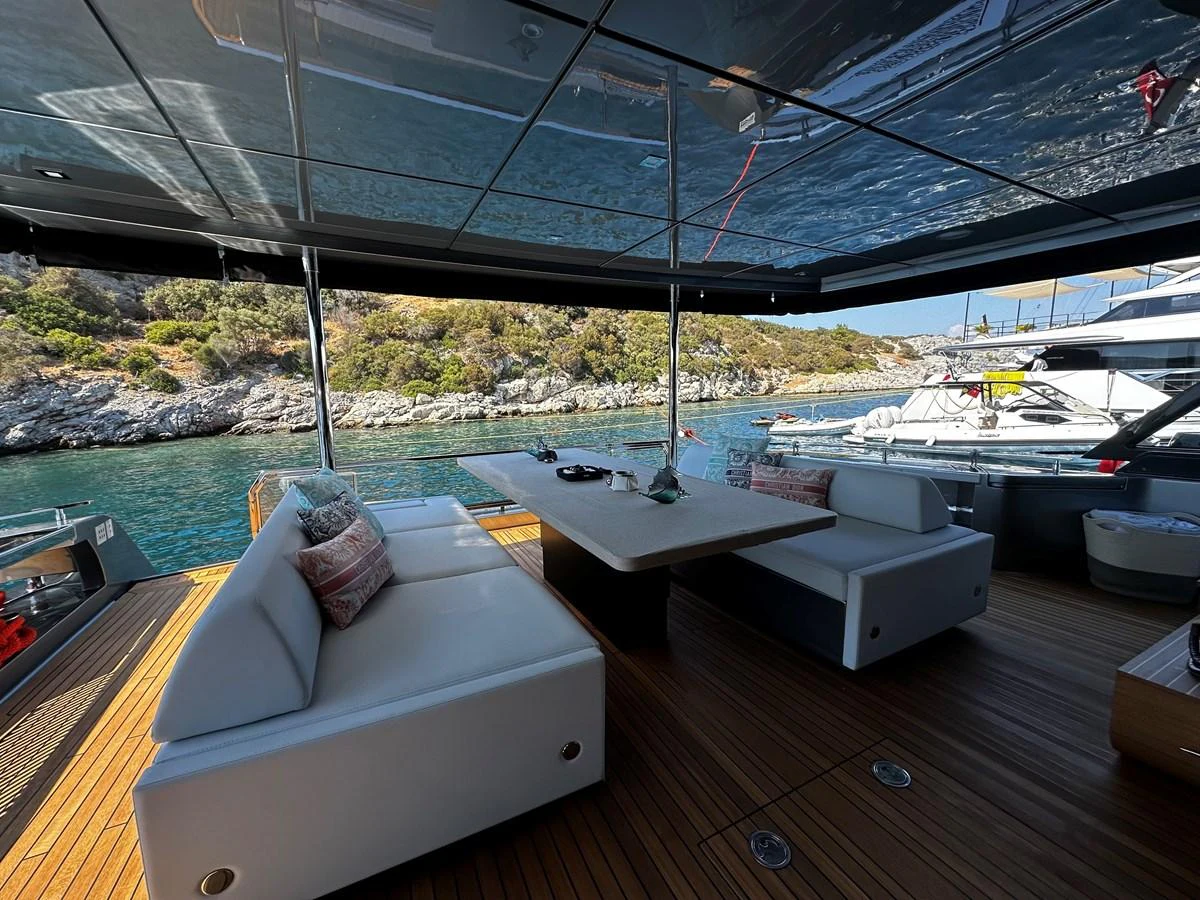 The aft deck features a comfortable seating area with a dining table, perfect for enjoying meals with a view of the water. aboard 4SEAS Yacht for Sale