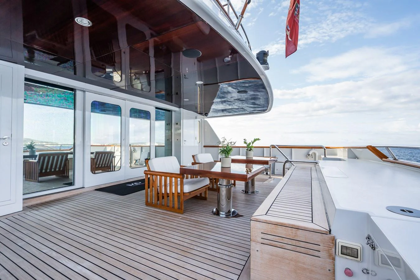 The aft deck features a stylish seating area with a wooden table and chairs, perfect for outdoor dining and relaxation. aboard MP5 Yacht for Sale