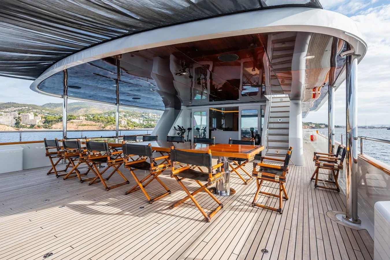 The aft deck features a spacious outdoor dining area with wooden chairs and a large table, perfect for alfresco meals. aboard MP5 Yacht for Sale