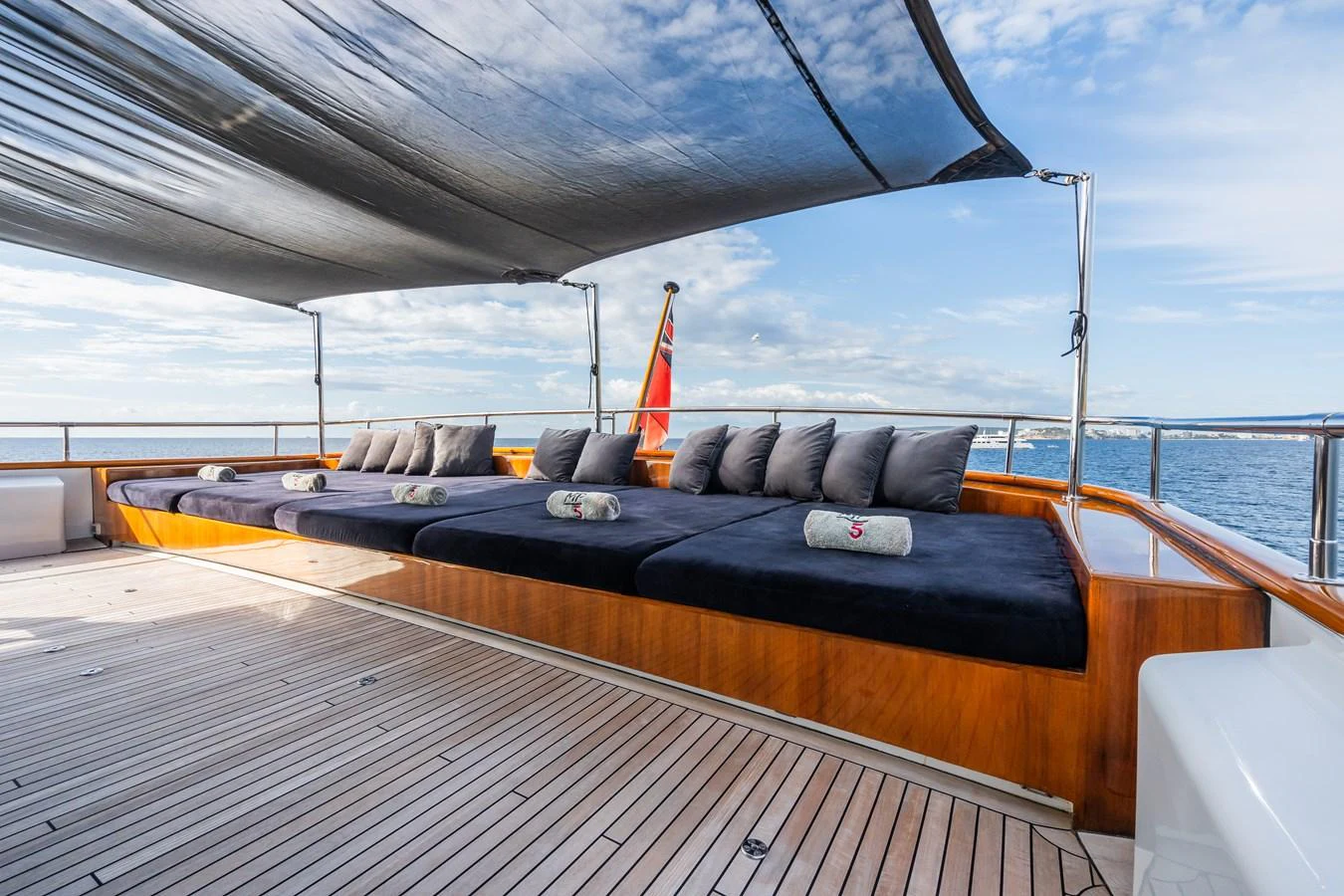The sundeck features a spacious lounging area with plush cushions and a retractable shade. aboard MP5 Yacht for Sale
