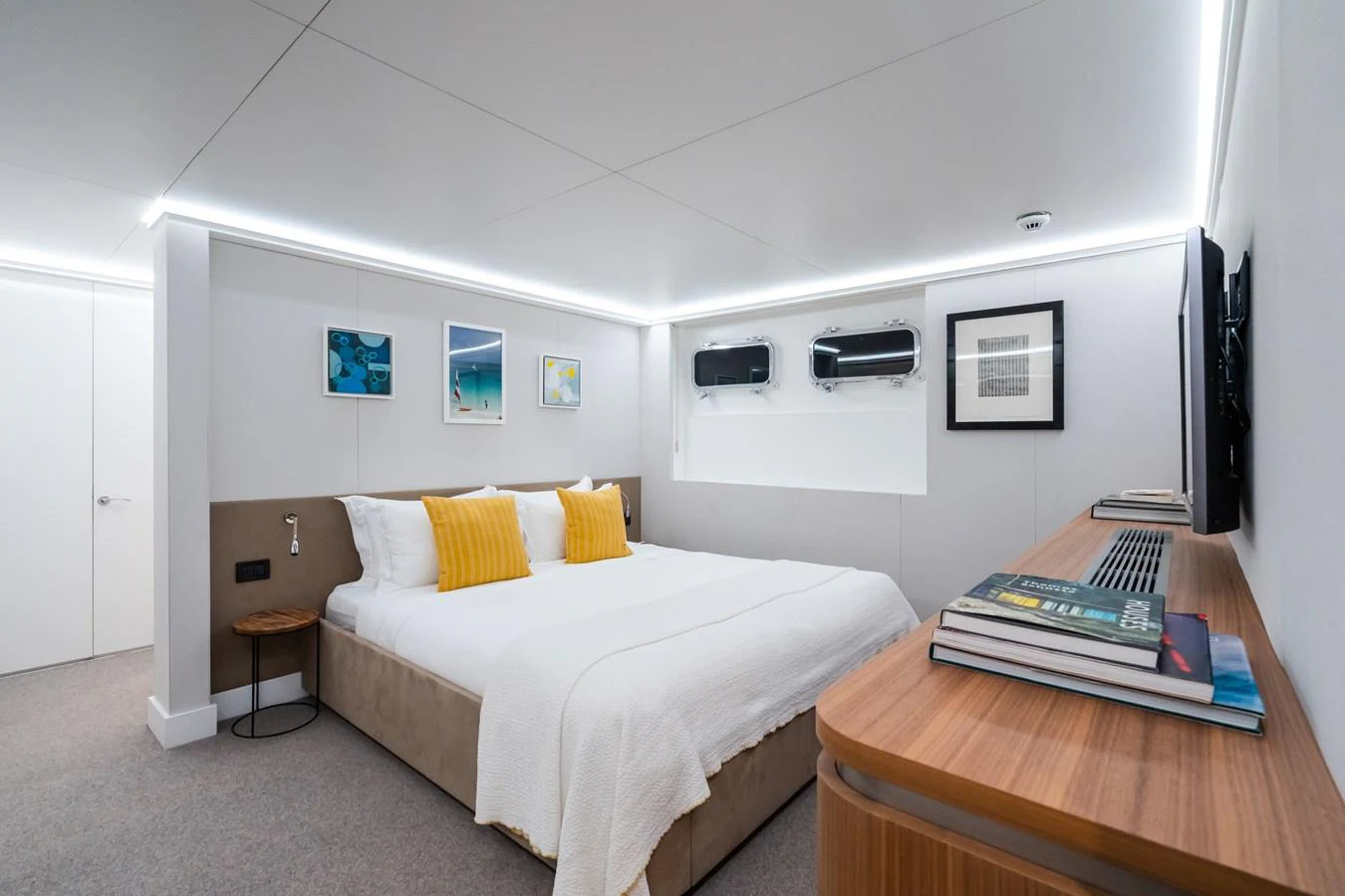 A luxurious stateroom featuring a large bed with white linens and yellow accent pillows, complemented by modern decor and ample natural light. aboard MP5 Yacht for Sale