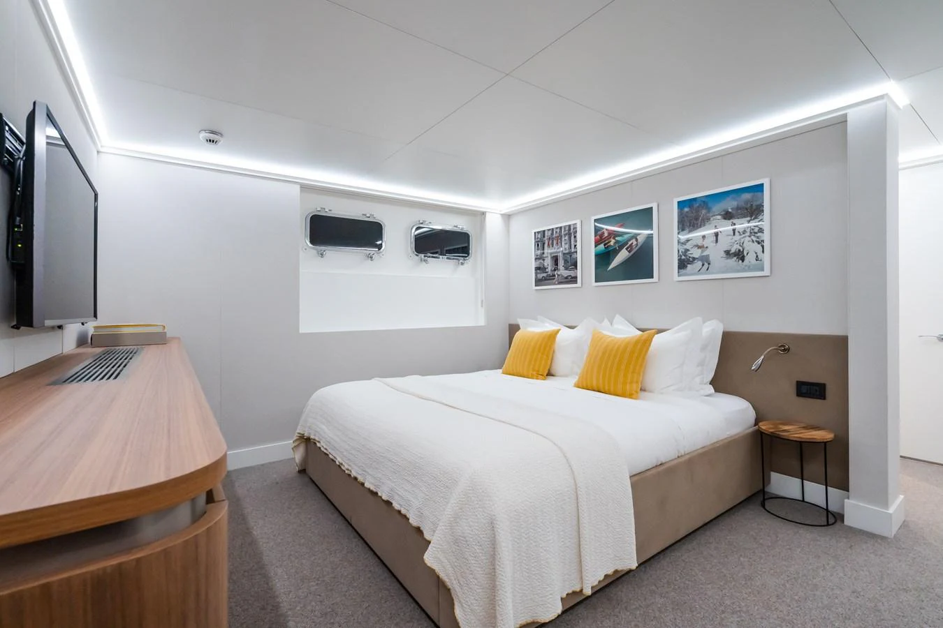 The stateroom features a comfortable bed with bright yellow accent pillows and modern decor. aboard MP5 Yacht for Sale
