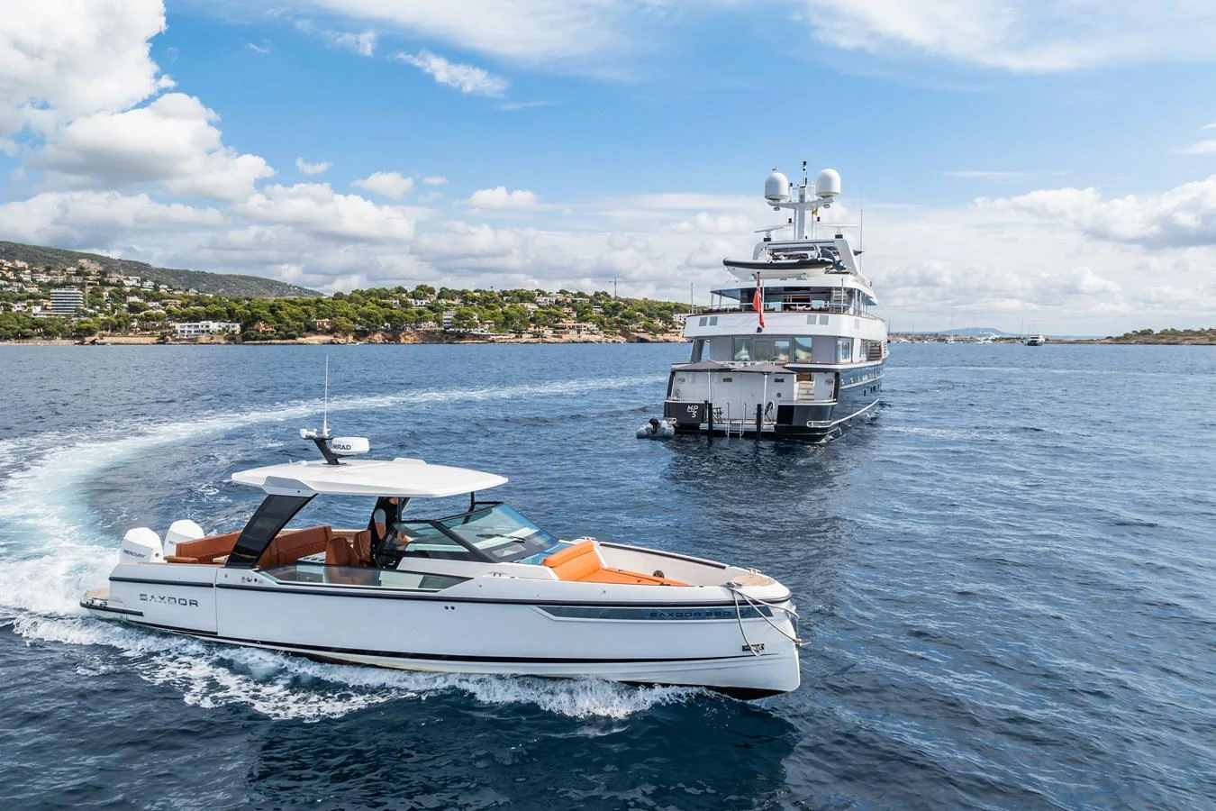 A sleek yacht cruises alongside a larger vessel in a picturesque coastal setting. aboard MP5 Yacht for Sale