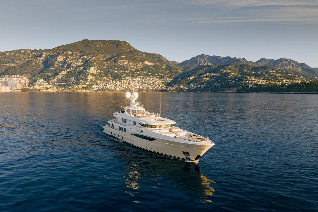 A luxurious yacht cruises gracefully on calm waters with a scenic mountainous backdrop. aboard GRACE Yacht for Sale