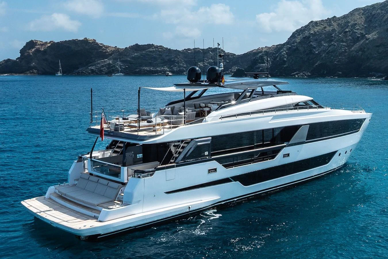 A sleek and modern yacht cruising in clear blue waters with a stunning backdrop of rocky islands. aboard FREYA Yacht for Sale