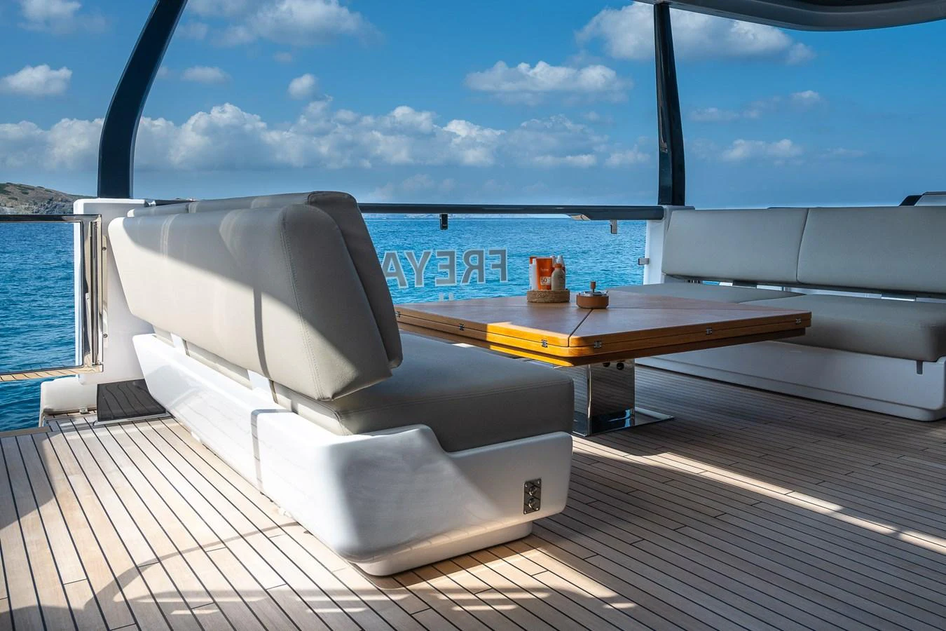 The aft deck offers a comfortable seating area with a wooden table, perfect for enjoying the ocean views. aboard FREYA Yacht for Sale