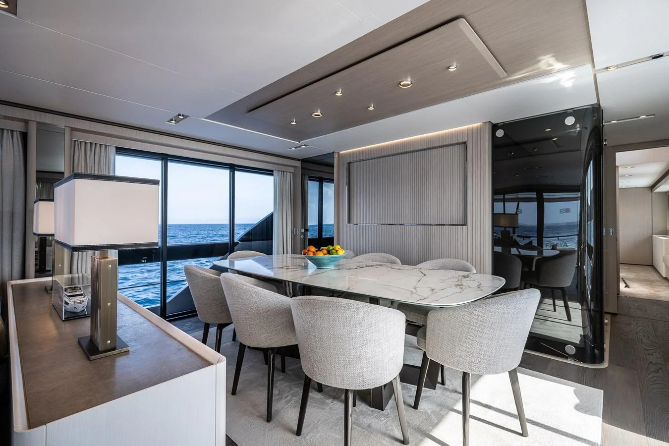 The yacht's dining area features a sleek, modern design with a large marble table and comfortable seating, offering stunning ocean views through expansive windows. aboard FREYA Yacht for Sale