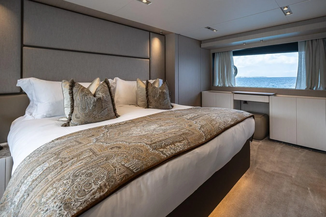 The master stateroom features a luxurious bed with elegant bedding and a large window offering a stunning sea view. aboard FREYA Yacht for Sale