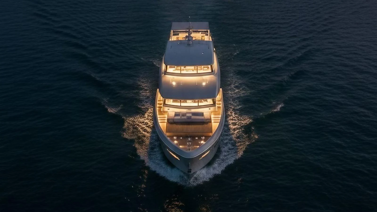 A luxurious yacht cruises forward, beautifully illuminated against the evening sea. aboard ISY 90 EXPLORA Yacht for Sale